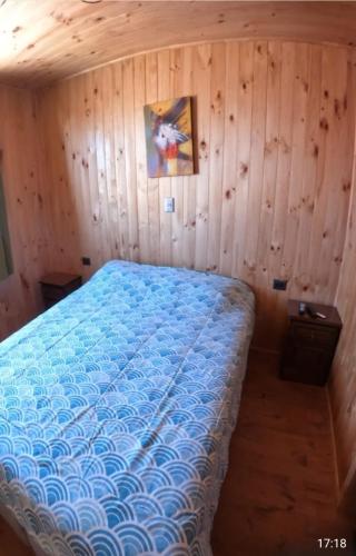 Cabañas Polymar el Tabo في إل تابو: غرفة نوم بسرير في جدار خشبي