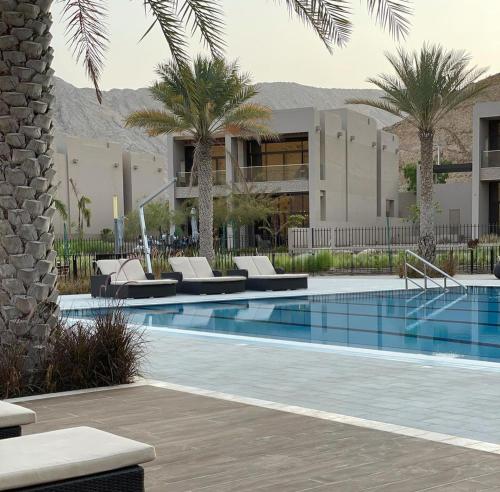 a swimming pool with lounge chairs and palm trees at Nameer bay in Bandar Jişşah