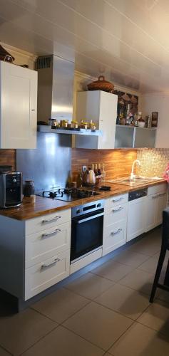 une cuisine avec des armoires blanches et un four à plaques de cuisson dans l'établissement Belle villa sur martigues, à Martigues