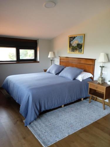 a bedroom with a large bed with a blue comforter at Casa Yañez in Chantada