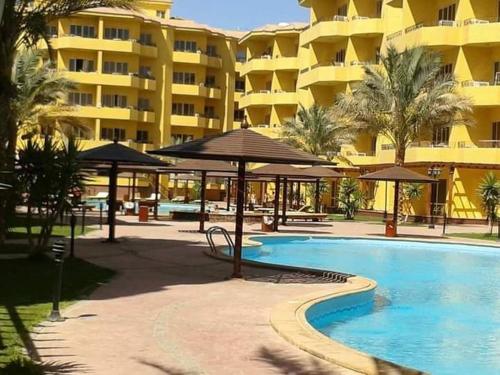 ein Pool mit Sonnenschirmen und ein großes Gebäude in der Unterkunft Hurghada British compound in Hurghada