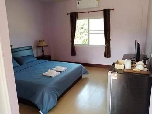 um quarto com uma cama azul e uma janela em หม่อนเมือง รีสอร์ท em Chiang Rai