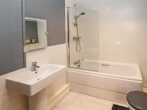 La salle de bains blanche est pourvue d'un lavabo et d'une baignoire. dans l'établissement 10 Mellor Way, à Grimsby