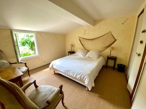 een slaapkamer met een bed, een stoel en een raam bij Gite la Maison de la Pimpine Lignan de Bordeaux in Lignan-de-Bordeaux