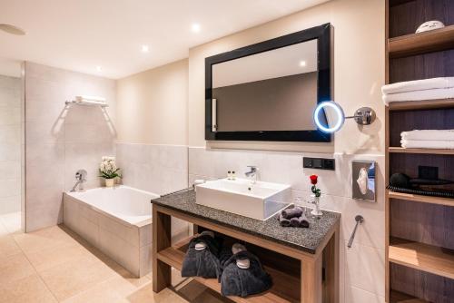 a bathroom with a sink and a tub and a mirror at Hotel Kaliebe in Trassenheide