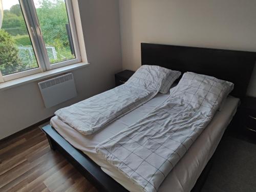 an unmade bed in a room with two windows at Tonkielek - Domek z Jacuzzi Nad Rzeką Bug in Tonkiele