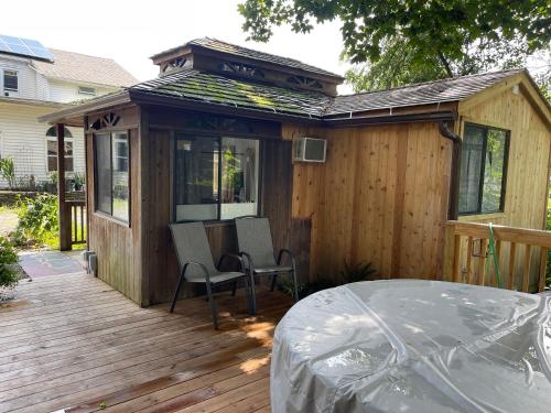 Cabaña de madera con terraza con mesa y sillas en Creekside Fantasy Inn en Hudson