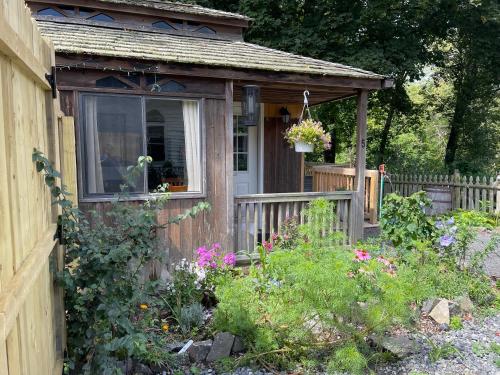 a small wooden shed with a window and flowers at Creekside Fantasy Inn in Hudson