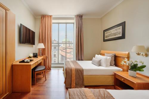 a hotel room with a bed and a desk and a window at Hotel Dei Cavalieri Milano Duomo in Milan