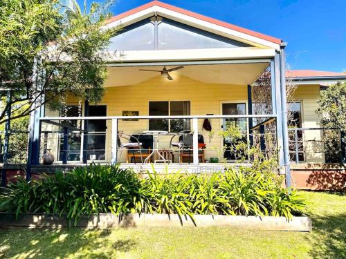 a yellow house with a large glass door at Bello Cottage in Bellingen