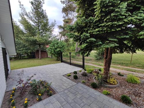 a courtyard with a tree and a fence at Tonkielek - Domek z Jacuzzi Nad Rzeką Bug in Tonkiele