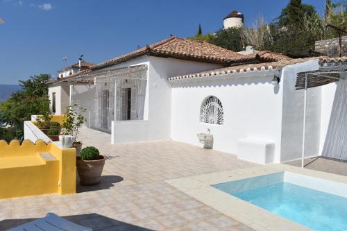 a white house with a swimming pool in front of it at Chez Le Goff in Hydra