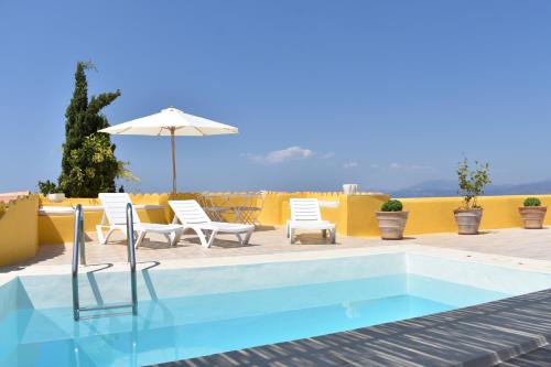 a swimming pool with white chairs and an umbrella at Chez Le Goff in Hydra