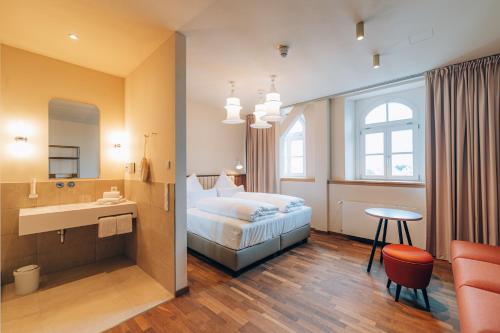 a bedroom with a bed and a sink and a mirror at Hotel Amalia - Boutique Hotel in Landshut