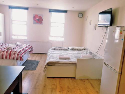 een kleine kamer met 2 bedden en een koelkast bij Cosy Studio Flat in Great Locationin London in Londen