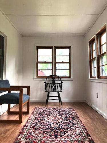 a room with a rug and a chair and two windows at Stream House (The Lorca, Catskills) in Shandaken