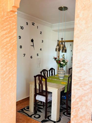 a dining room table with chairs and a clock on the wall at Oualidia29 in Oualidia