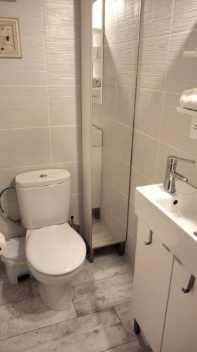 a white bathroom with a toilet and a sink at Beachfront Apartment with Sea Views & Private Parking in San Pol de Mar