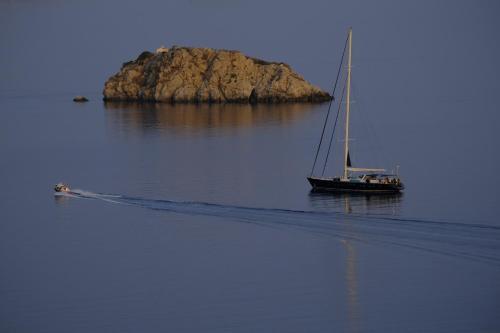 a boat on the water with an island in the background at Chez Le Goff in Hydra