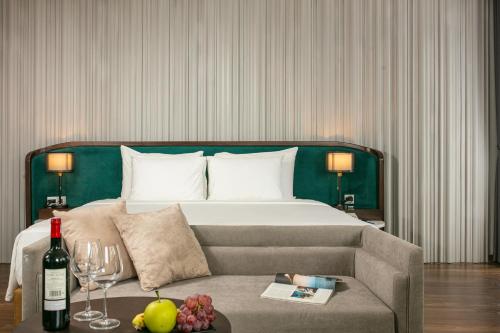 a hotel room with a bed and a couch and wine glasses at MAY DE VILLE Lakeside Hotel in Hanoi