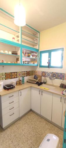 une cuisine avec des placards blancs et des toilettes dans l'établissement בית הלב, à Nahariya