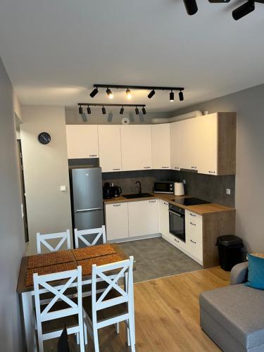 a kitchen with white cabinets and a table in a room at N&S Apartament na Lisiej in Zielona Góra