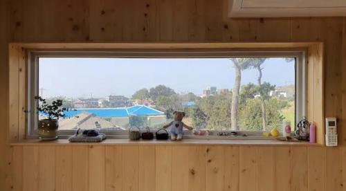 a window with a doll sitting on a window sill at Mirine Jeju in Jeju