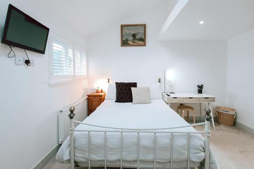 a white bedroom with a bed and a desk at The Pembroke Studio By Richmond Park in Kingston upon Thames