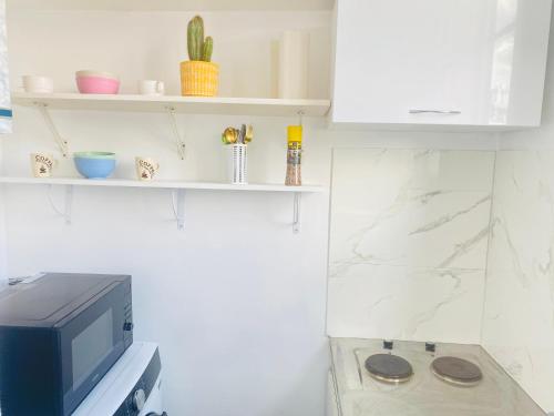 een kamer met een tv en een aanrecht met planken bij Charmant studio calme, proche La Défense & Paris in La Garenne-Colombes