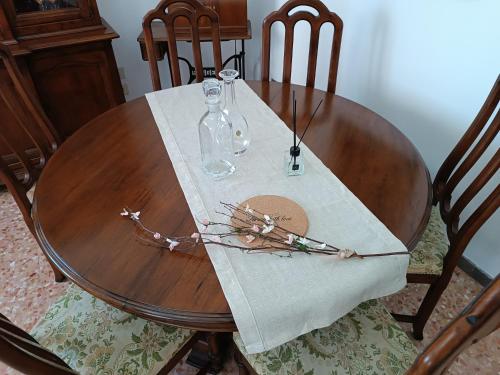 a wooden table with a glass bottle and flowers on it at La Vista Storica in Piombino