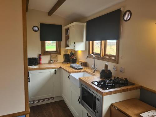 a kitchen with white cabinets and a stove top oven at Boyce Fen Farm Retreat Glamping & Fishery in Wisbech