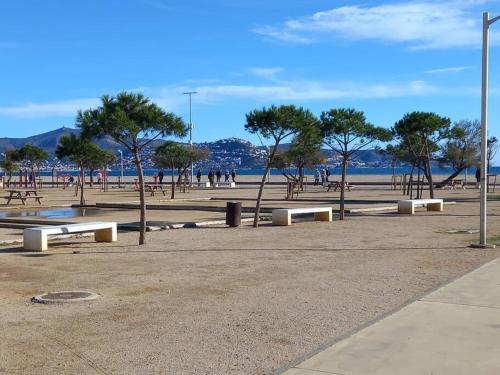 un parque con bancos y árboles en la playa en San Lluis Apartamento vistas mar delante playa Empuriabrava, en Empuriabrava