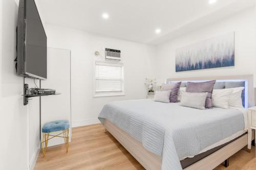 a white bedroom with a bed and a flat screen tv at 316 Footloose #3 in Hollywood