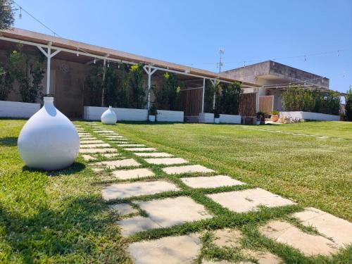 Un vaso bianco, seduto sull'erba in un giardino. di Masseria Tumara Rooms and Apartments a Otranto