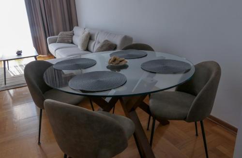 a dining room table with four chairs and a couch at Apartments Radovic in Podgorica