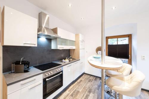 a kitchen with white cabinets and a small table at Ferienwohnung Annemarie in Mieders