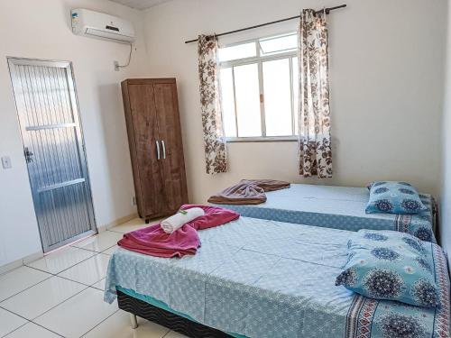 two beds in a room with a window at Pousada BR101 in Angra dos Reis