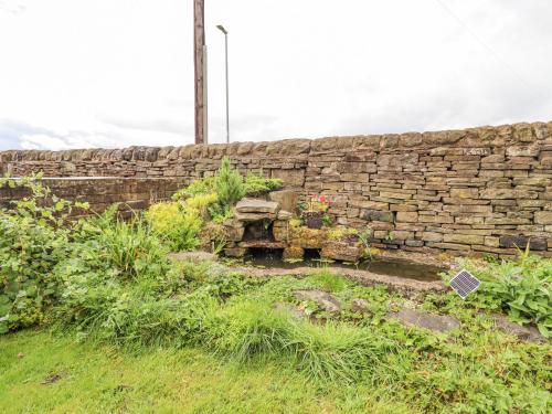 a stone wall with a bench in a garden at Ash Tree Barn in Clayton