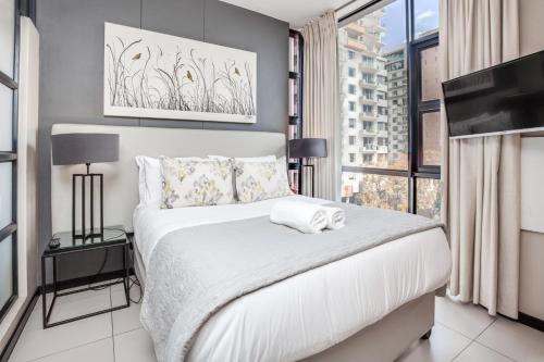 a bedroom with a white bed and a large window at Urban Oasis Apartments at The Vantage in Johannesburg