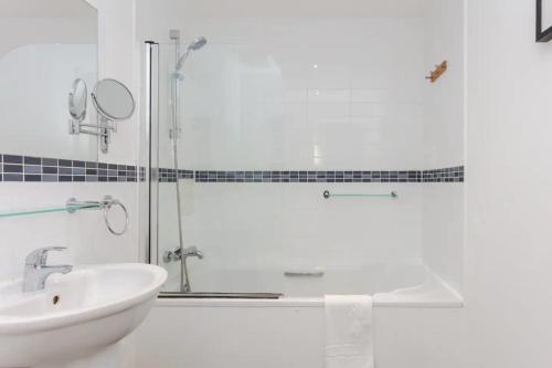 a white bathroom with a shower and a sink at Bright & Airy 1 Bedroom Apartment in Trendy Peckham in London