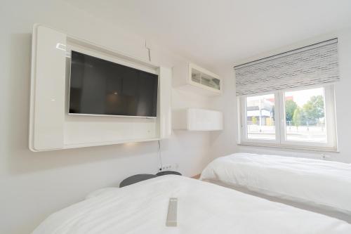 Dieses weiße Zimmer verfügt über 2 Betten und einen Flachbild-TV. in der Unterkunft Arena Rooms Zagreb in Zagreb