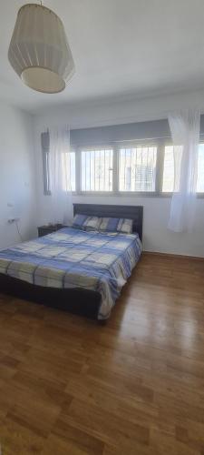 1 dormitorio con 1 cama en una habitación con ventanas en פנטהאוז בירושלים, en Bayit Wegan