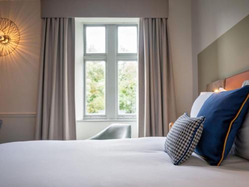 a bedroom with a white bed with a window at voco Edinburgh - Royal Terrace by IHG in Edinburgh
