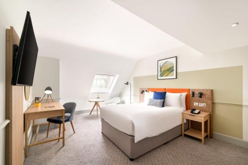 a hotel room with a bed and a desk and a tv at voco Edinburgh - Royal Terrace by IHG in Edinburgh