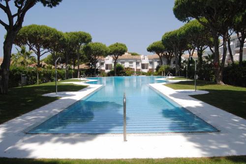 a swimming pool in a park with trees at Chiclana Costa in Chiclana de la Frontera