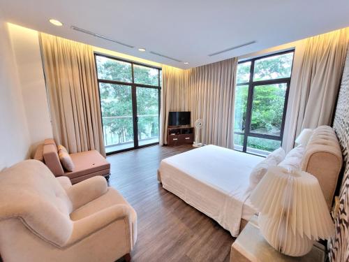 a large bedroom with a bed and two chairs at Bạch Yến T111-Happy Villa Đại Lải Resort in Vĩnh Phúc