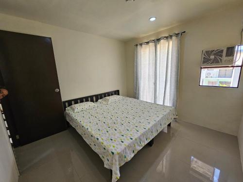 a small bedroom with a bed in front of a window at Casa Mira Coast Apartment with Motorbike in Dumaguete