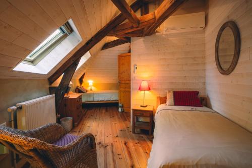 - une chambre mansardée avec un lit et deux chaises dans l'établissement Le Gîte de l'Ormoy, à Saint-Laurent