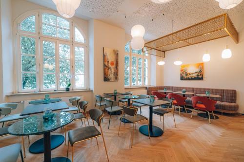 a restaurant with tables and chairs and windows at Hotel Amalia - Boutique Hotel in Landshut