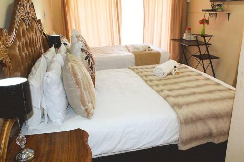 um quarto com uma cama com lençóis brancos e almofadas em Sheeroh's Place em Burgersfort